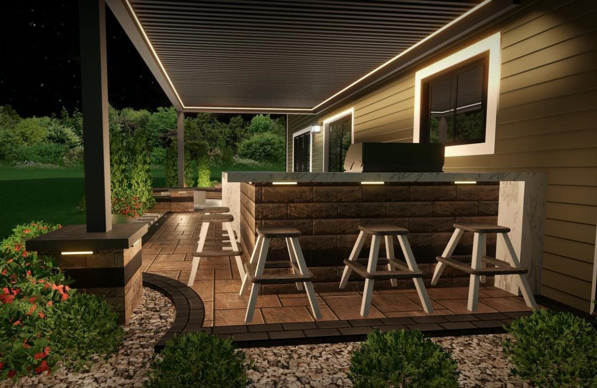 Modern outdoor kitchen with a stone bar, white stools, and a pergola on a stone patio.