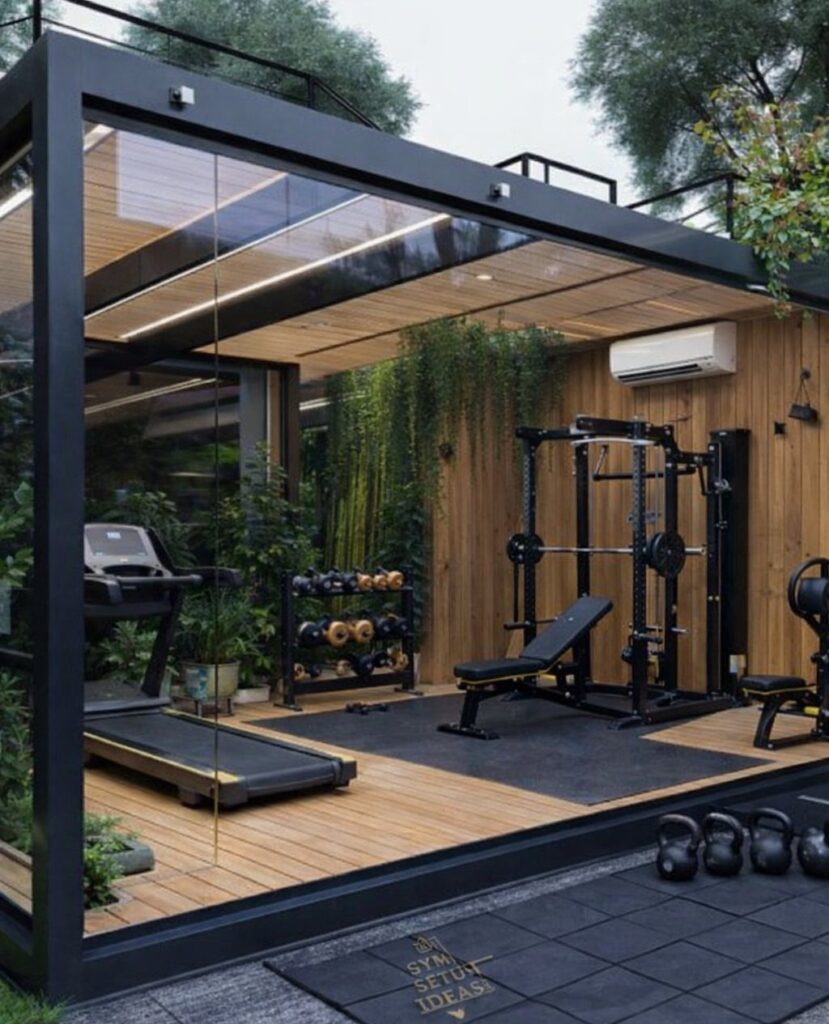 Modern glass-walled backyard gym shed containing a treadmill, weight rack, and power rack.